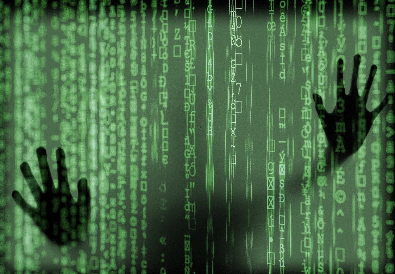 Shadow hands against screen filled with code representing pitfalls to avoid in bespoke software development