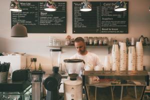Small business owner behind coffee shop counter representing custom software and outsourcing
