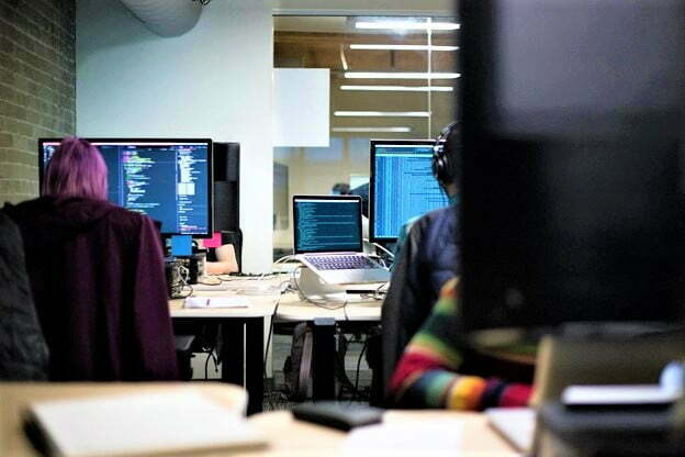 Website developers in office in front of computer screens representing the importance of latest technology in the workplace