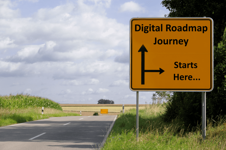 Road with grassy verges and large yellow square sign that Says Digital Roadmap Journey, Starts Here.