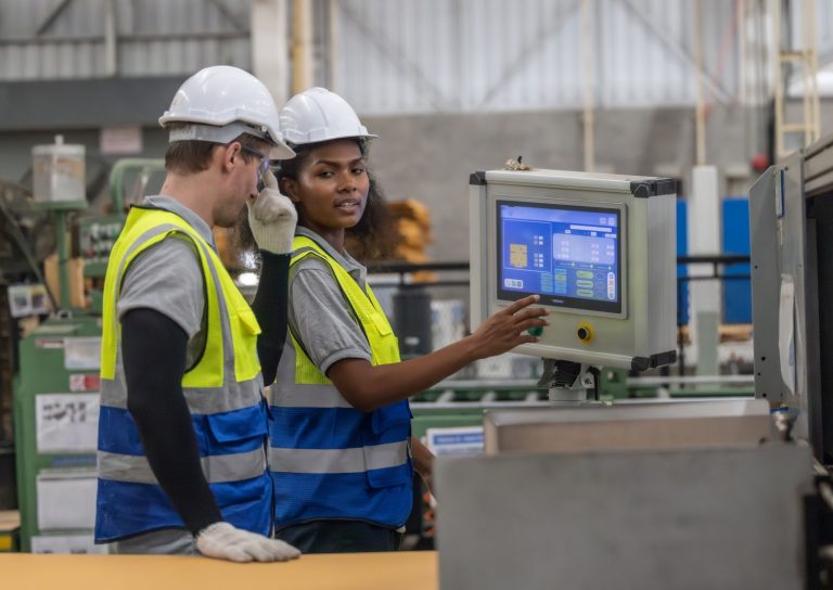 ERP Pricing - Photo showing 2 factory workers looking at ERP software on a terninal.