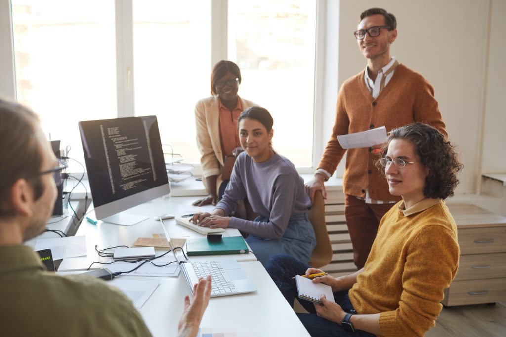 Photo showing a group of developer talking, representing discussing acceptance criteria for a software project.