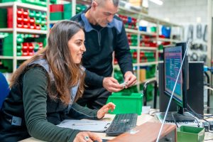 Photo of two workers in a warehouse, using stock control software.