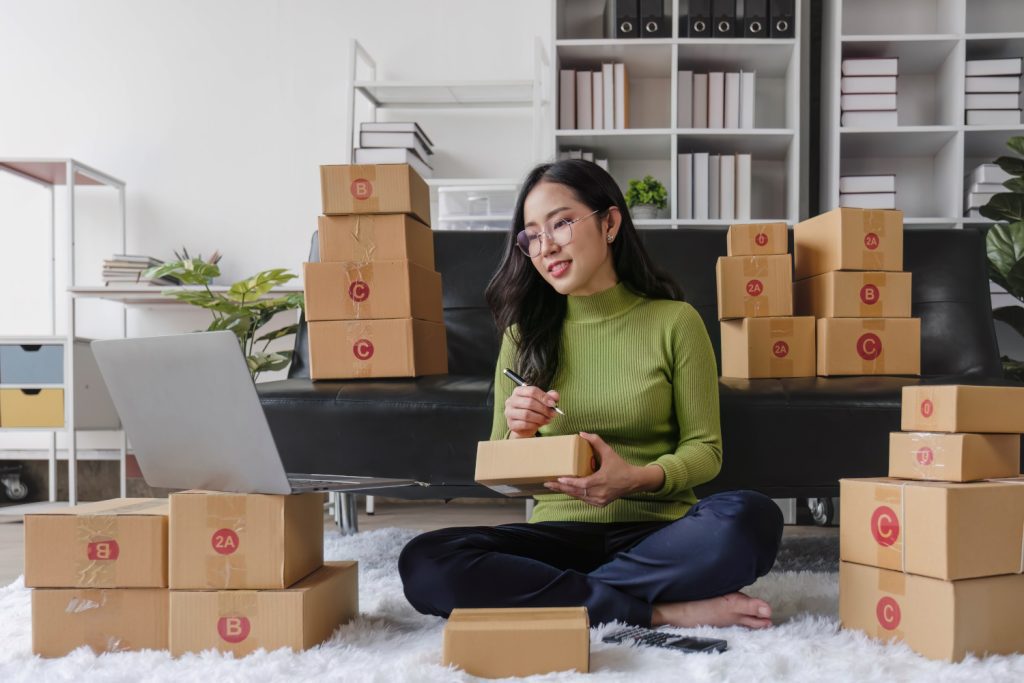 Picture of a female business owner using an e-commerce website, surrounded by packages to represent e-commerce developer.