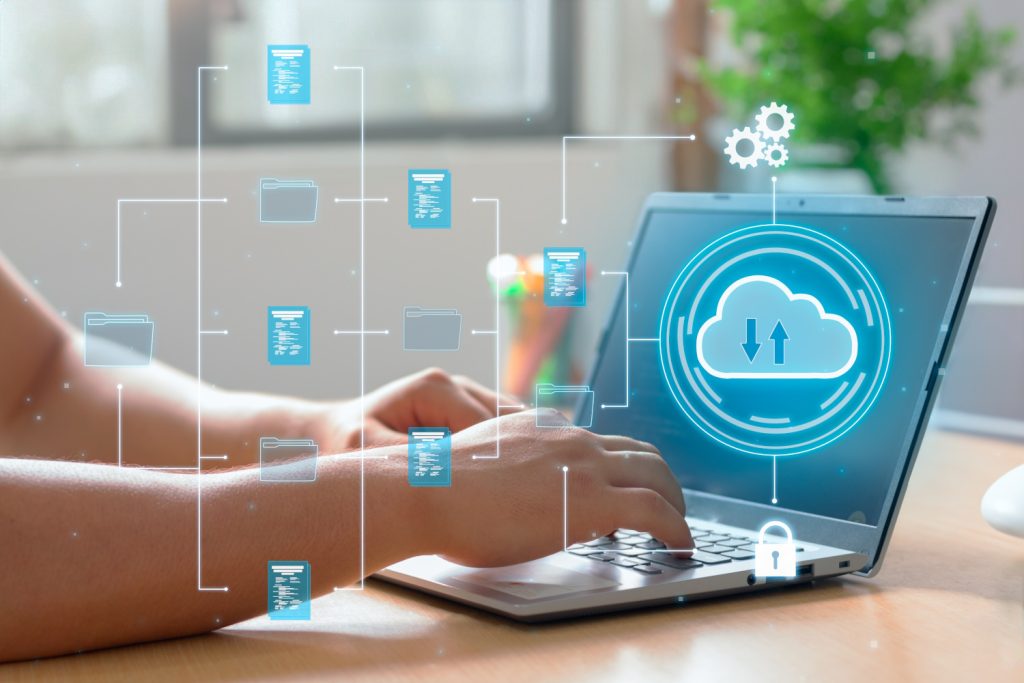 Man using a laptop with cloud on the screen and icons floating. to represent hosting a web application, in the cloud.