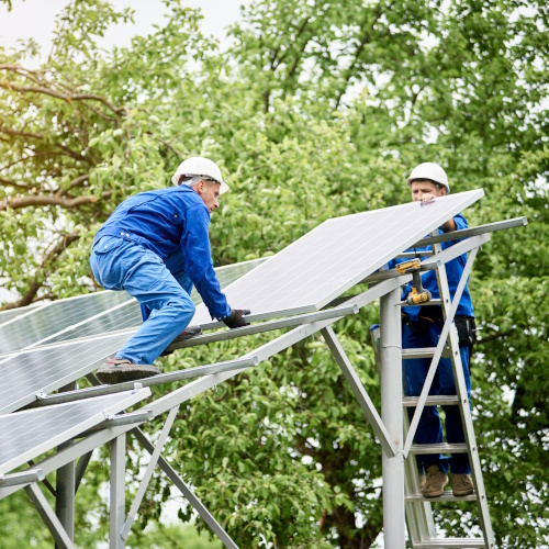 Photo showing two men on a roof installing solar panels to represent the construction industry.