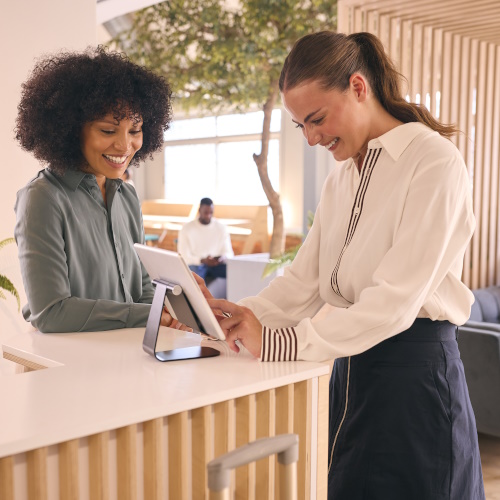 Photo showing a woman checking into a hotel and a receptionist, to represent the hospitality industry.