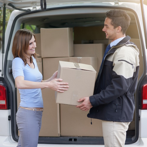 Photo showing a delivery driver outside his van handing over a parcel to represent a transport firm.