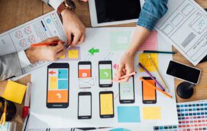 Photo of people with papers and layouts for mobile devices to represent mobile application developers.