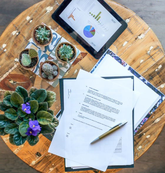 Photo of a table with a tablet, plants and an SLA document to represent SLA meaning.
