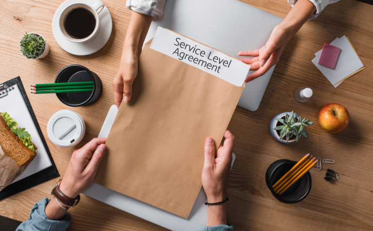 Photo of a desk, hands holding an envelope, with service level agreement written on it.