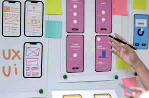 Photo of whiteboard with hand drawn application layouts outs and printed application layouts on mobile phones.